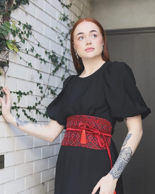 Red embroidered tie belt worn over a black dress