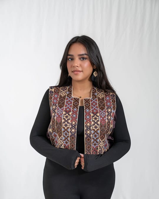 Front view of an open vest with columns of brown, gold and blue embroidery over a black top
