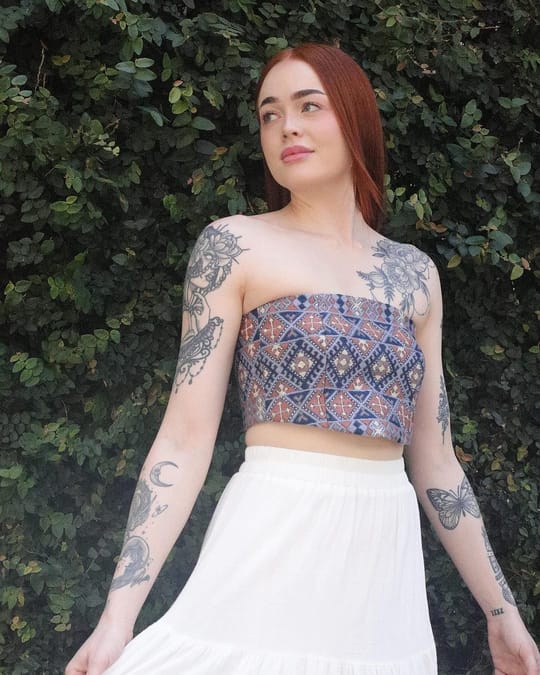 Model in a strapless indigo and rust embroidered crop top with a white skirt