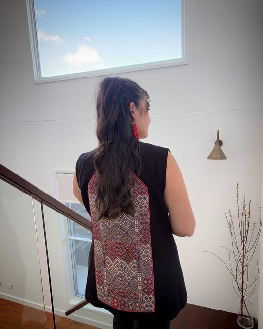 Back view of a black vest with a red and cream embroidered panel