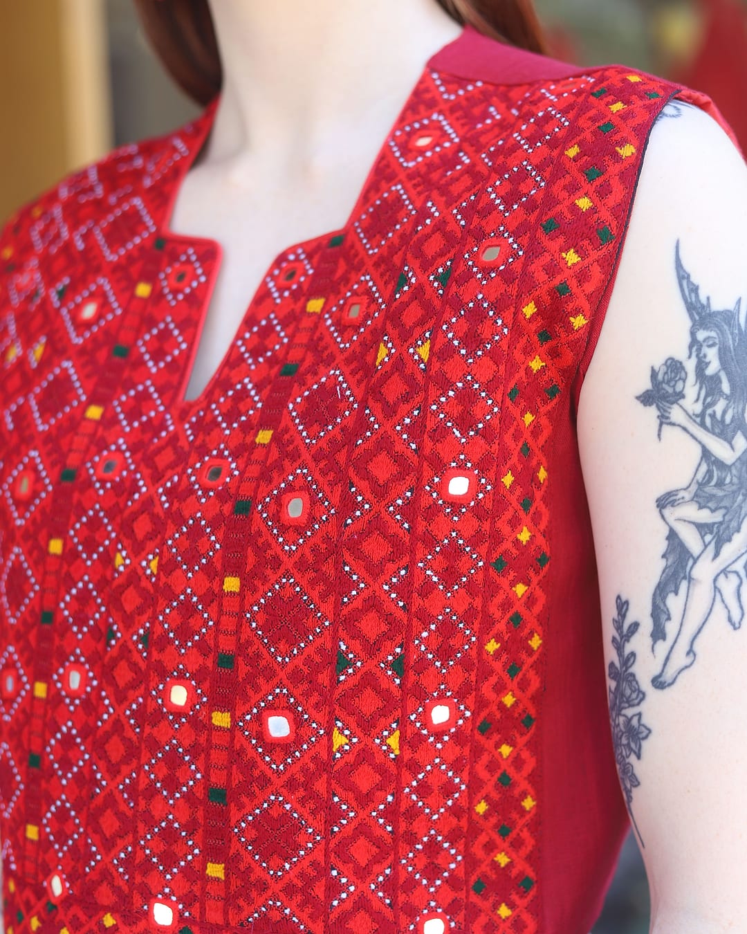 Close view of the red embroidery, small mirrors and diamond patterns on the Crimson Mirror Vest