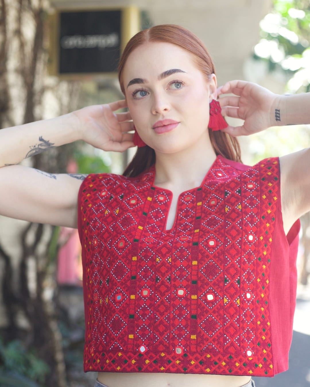 Model in a cropped red Balochi embroidered vest with mirror work and a split neckline, worn with denim