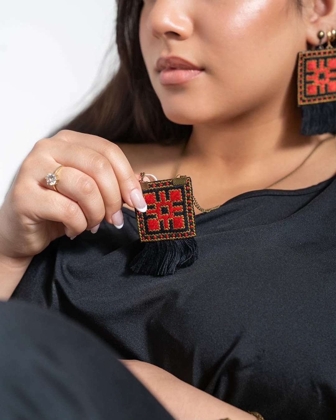 Close view of the square embroidered pendant held in the hand