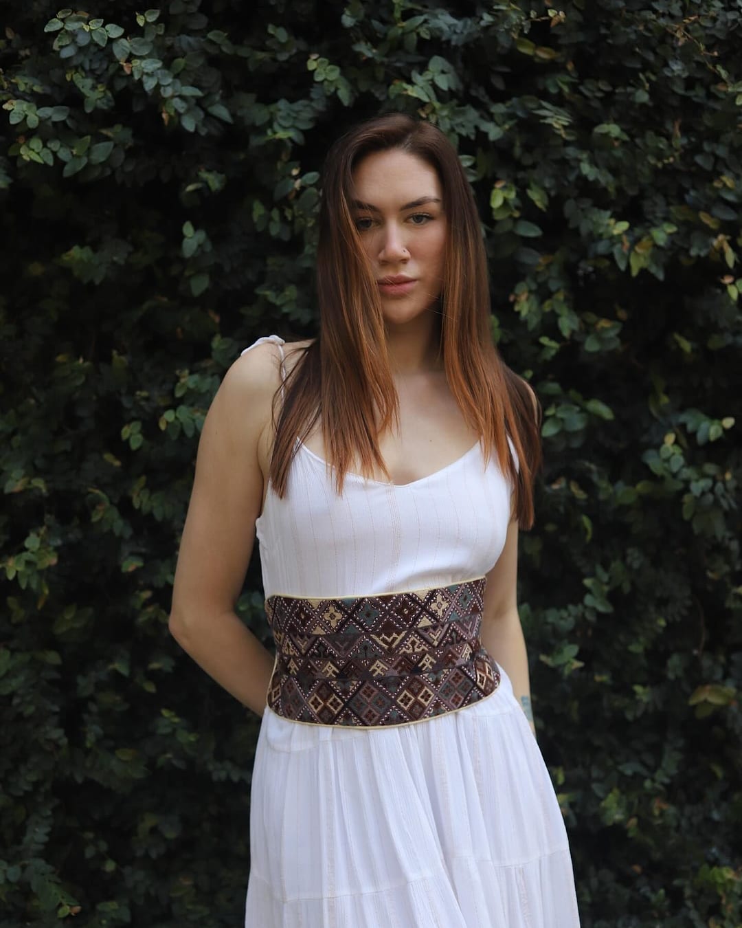 Wide brown and black embroidered belt worn over a white dress