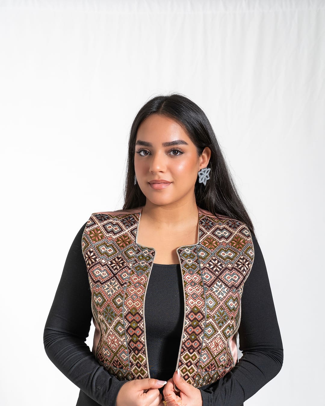 Front view of a geometric embroidered vest worn over a black top