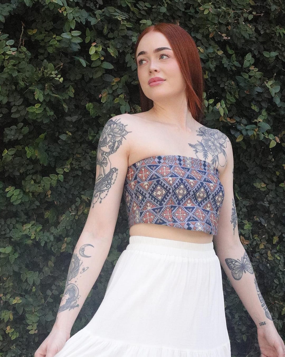 Model in a strapless indigo and rust embroidered crop top with a white skirt