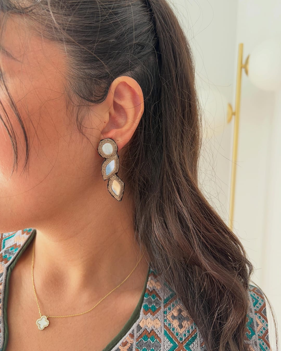 Silver mirror-work drop earring worn with an embroidered vest