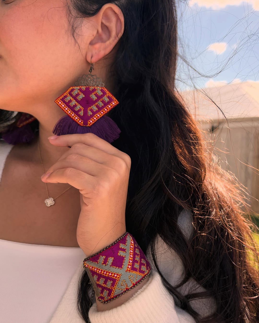 Close view of the pink and purple embroidered earring and bracelet