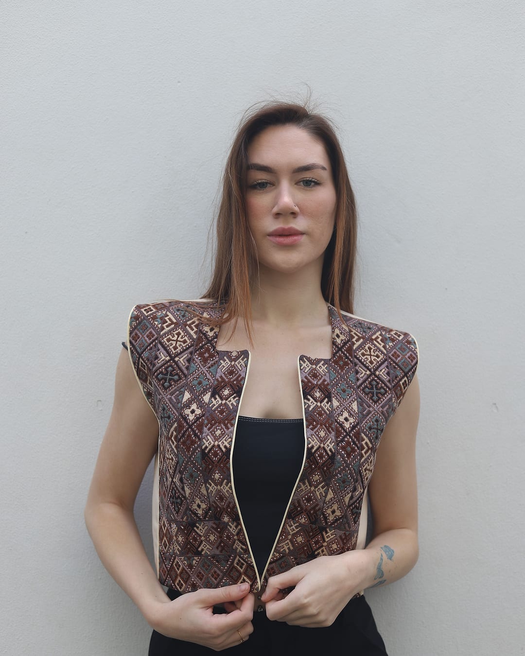 Front view of a brown, pink and cream lattice embroidered vest with cream piping