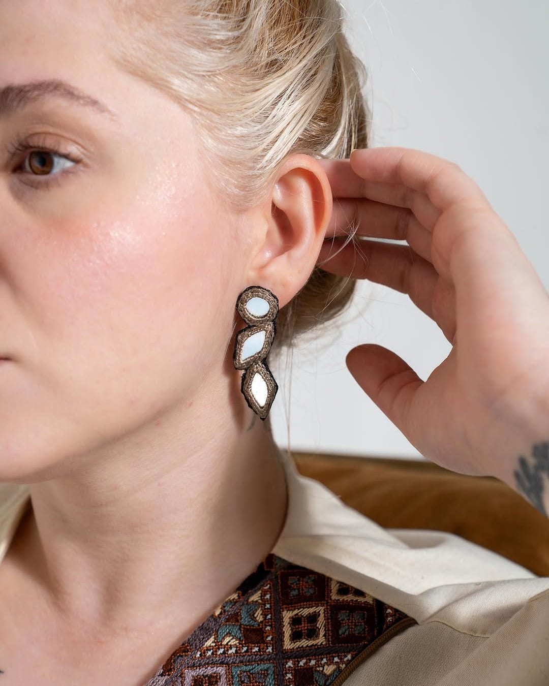 Mirror work drop earring worn with a cream linen top